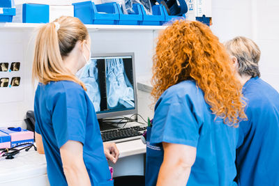 Mature nurse with colleagues examining x-ray image on computer at hospital