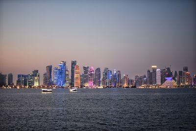 River by illuminated modern buildings against clear sky