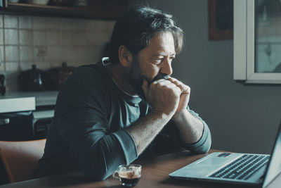 Side view of young man using laptop at home