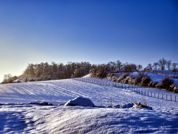 Snow covered landscape against clear blue sky