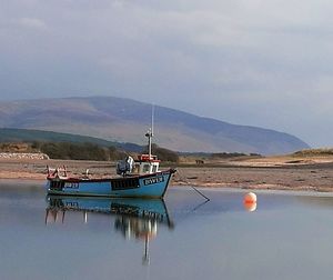 Fishing boats moored in sea against sky