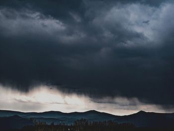 Silhouette of mountain against cloudy sky