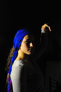 Woman wearing blue headwear against black background