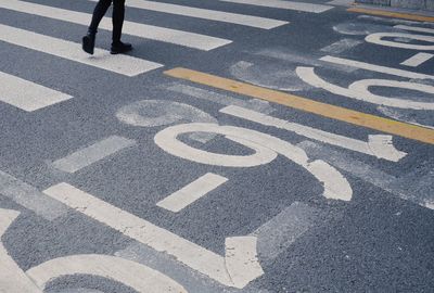 Low section of person walking on road in city