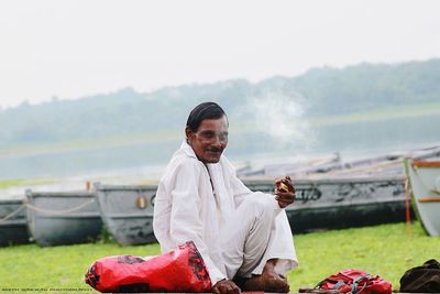 Portrait of man sitting on field against sky
