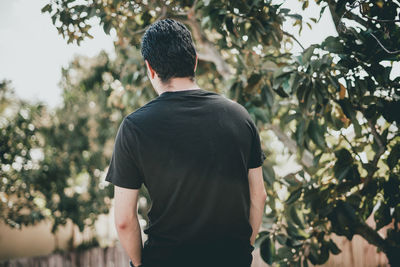 Rear view of man standing against trees