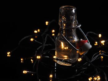 Close-up of illuminated glass bottle against black background