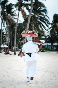 Rear view of female vendor selling food at beach