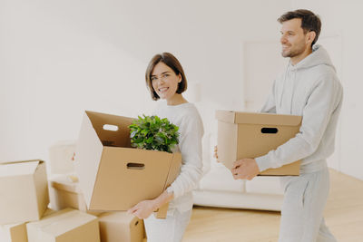 Smiling couple carrying cardboard boxes in new home