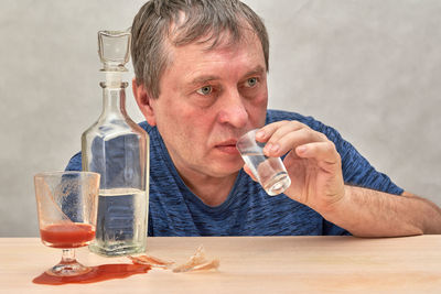 Portrait of mid adult man drinking glass on table