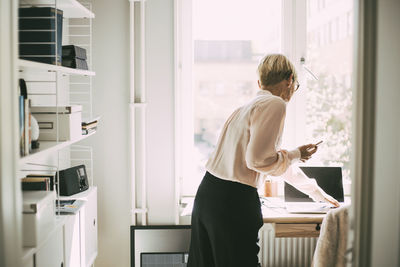 Woman standing by window at home