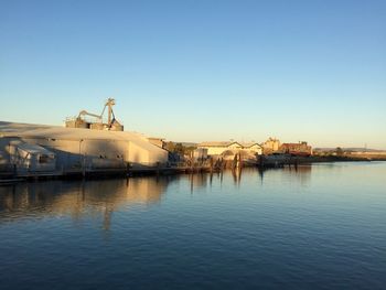 Commercial dock by river against clear sky