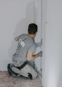 A young builder is plastering a doorway.