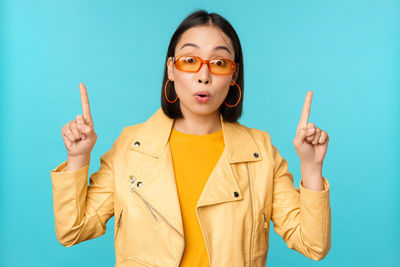 Portrait of young woman gesturing against blue background
