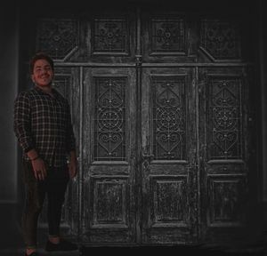 Portrait of young man standing against door