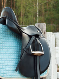 Close-up of saddle on wooden railing at barn