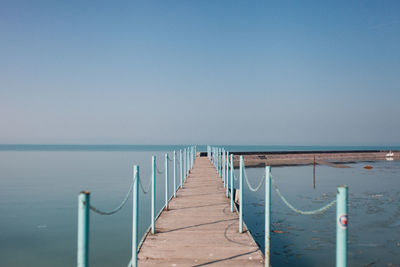 Wooden pier on sea against clear sky