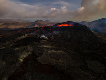 Active volcano on mountains against sky