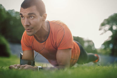Man in plank position on grassy field at park