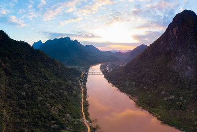 Scenic view of river amidst mountains against sky during sunset