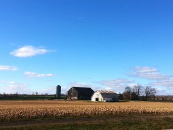 Barn on field against blue sky