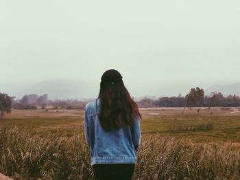 Rear view of woman standing on field against clear sky