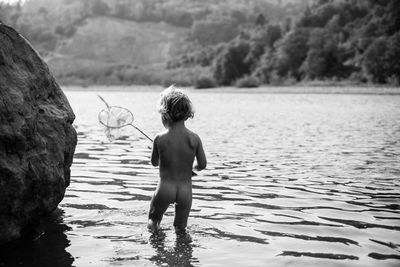 Rear view of boy with fishing net in lake