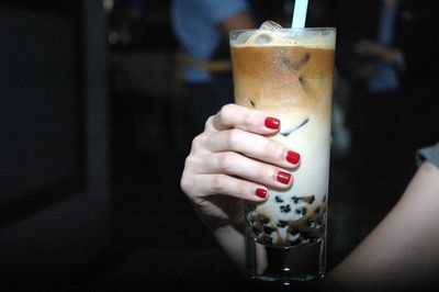 Midsection of woman holding iced coffee jelly in tall glass