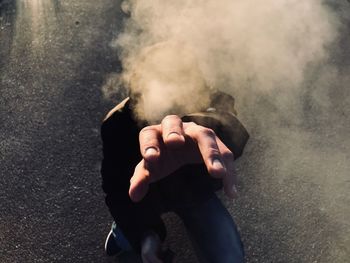 Close-up of man hand with smoke covering face on street