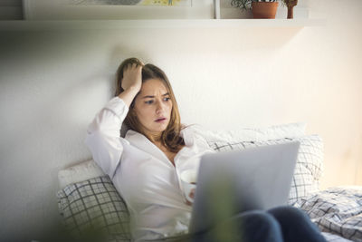 Young woman using laptop in bed