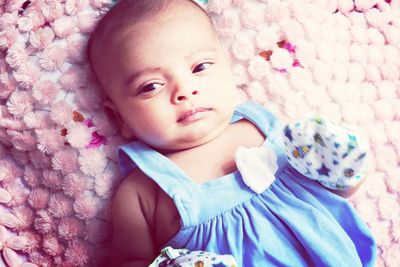 Portrait of cute baby girl lying on bed