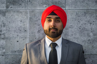 Portrait of smiling businessman wearing turban against wall