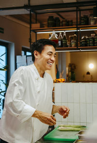 Happy male chef standing near counter at commercial kitchen in restaurant