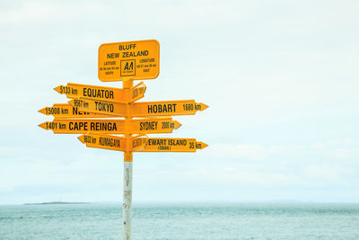 Close-up of yellow signs against sea and sky