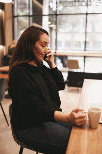 Adult serious business woman freelancer working in a coffee shop cafe using a laptop and phone