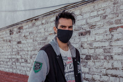 Portrait of young man with face mask in city against clear sky