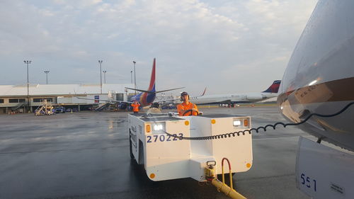 Man on airport runway against sky