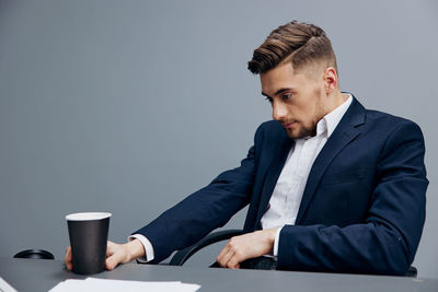 Young man using laptop while standing against white background