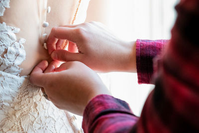 Dropped hands of person dressing bride during wedding