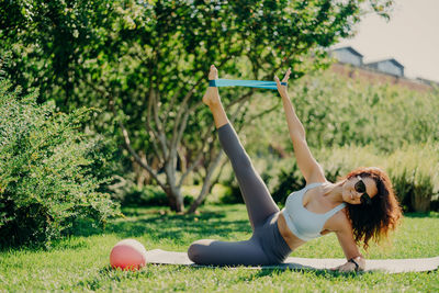 Woman exercising on mat with equipment in park