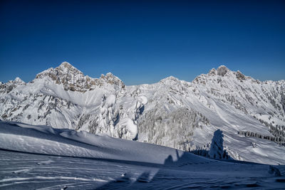 Scenic view of snowcapped mountains against clear blue sky