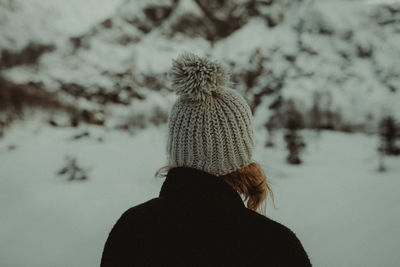 Rear view of woman with knit hat standing against trees during winter