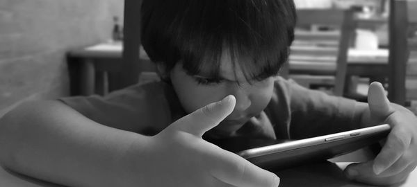 Close-up of boy using digital tablet at table