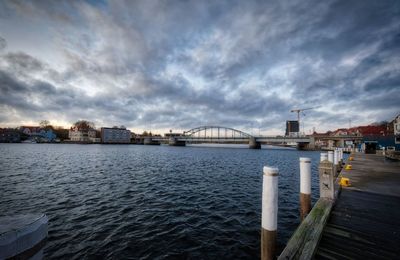 River by cityscape against sky during sunset