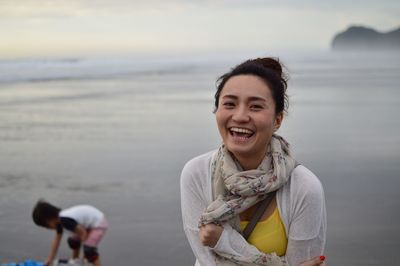 Portrait of smiling young woman standing at beach