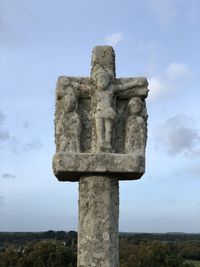 Low angle view of cross sculpture against sky