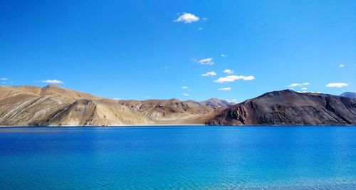 Scenic view of sea and mountains against blue sky