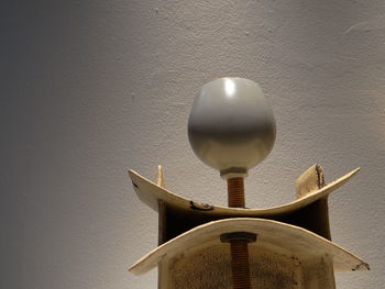 Close-up of electric lamp on table against wall