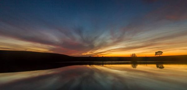 Scenic view of dramatic sky over lake during sunset