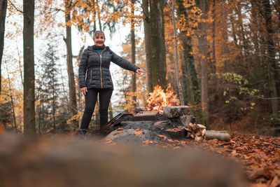 Woman standing by campfire in forest